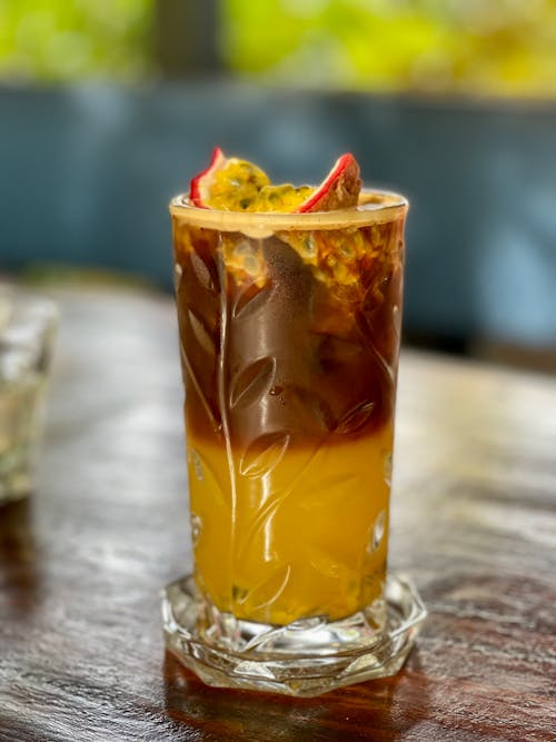 Close-up of a Glass with Coffee with Juice and Passion Fruit on Top 