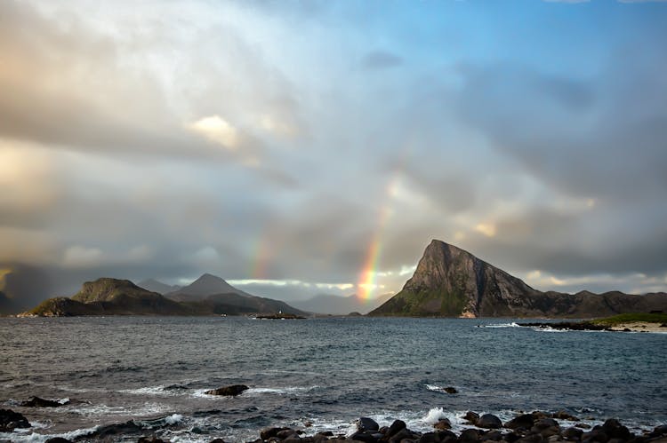 Clouds And Rainbows Over Rocks On Sea Shore