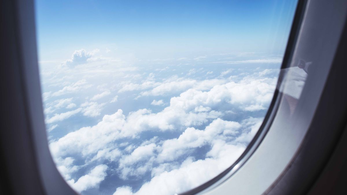 Breathtaking view of clouds and blue sky through an airplane window during flight.