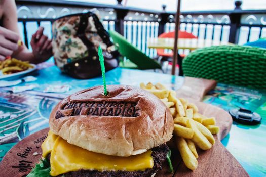 Tasty cheeseburger with fries served on a vibrant outdoor table, perfect for a casual meal.