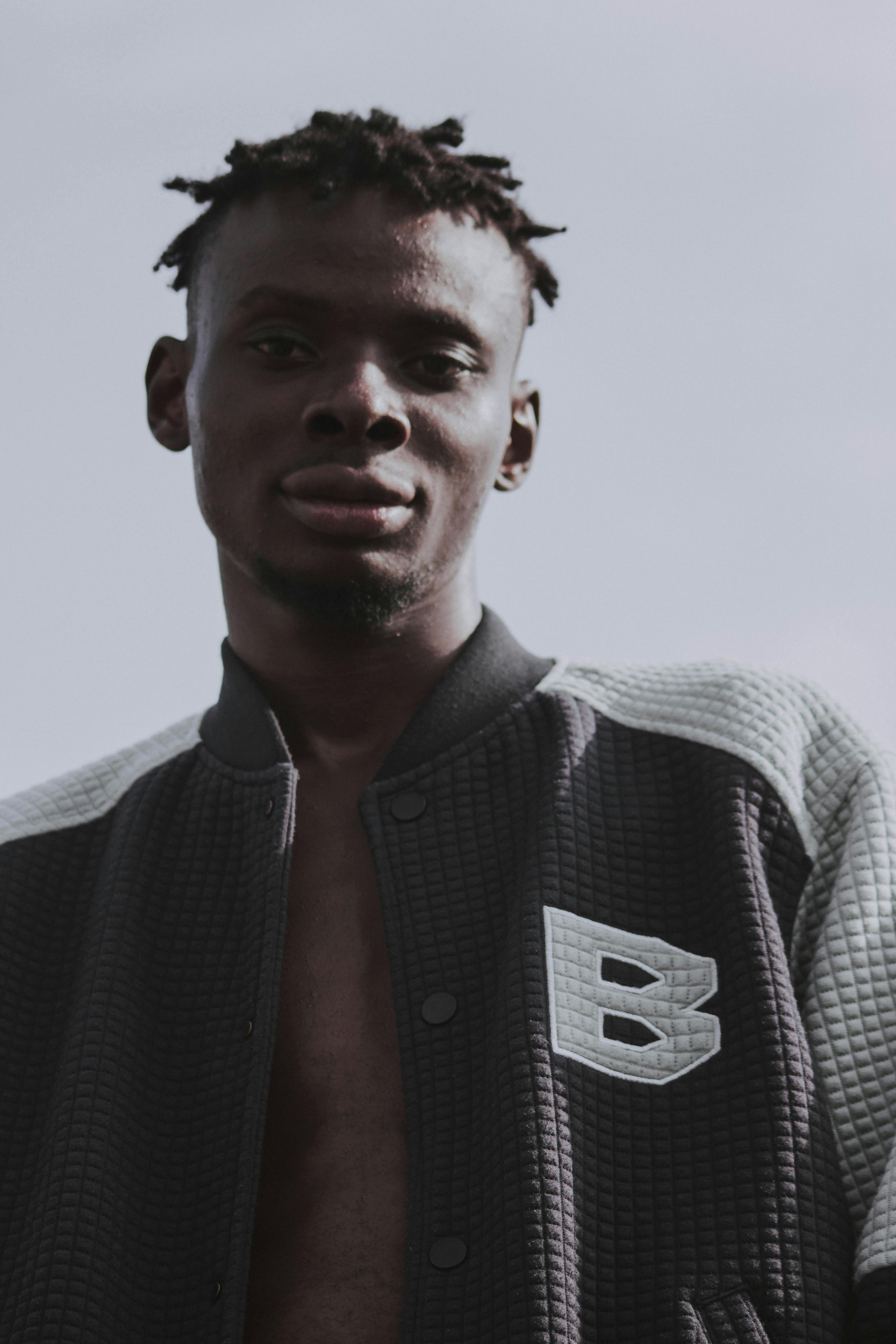 Fashionable young man with dreadlocks in sportswear poses confidently outdoors in Lagos, Nigeria.