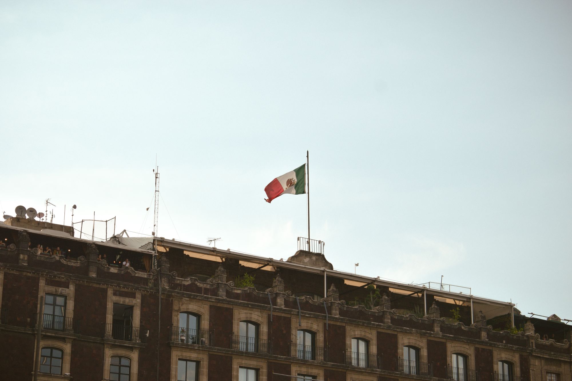 Mexican flag waving atop a historic building in Mexico City, showcasing cultural pride.