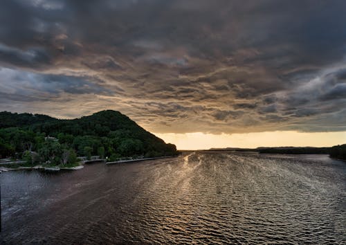 Aerial Photography of Ocean and Green Mountain during Sunset