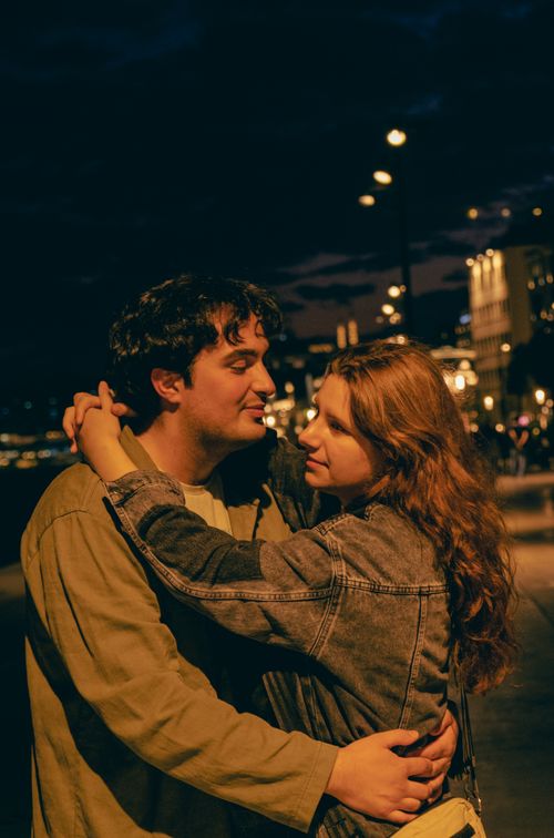Free Couple embracing on a city street at night, under street lights, evoking romance. Stock Photo