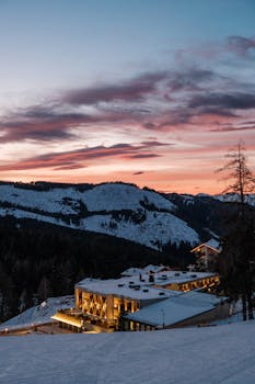 Stunning winter landscape with illuminated luxury resort nestled in snow-covered mountains during sunset