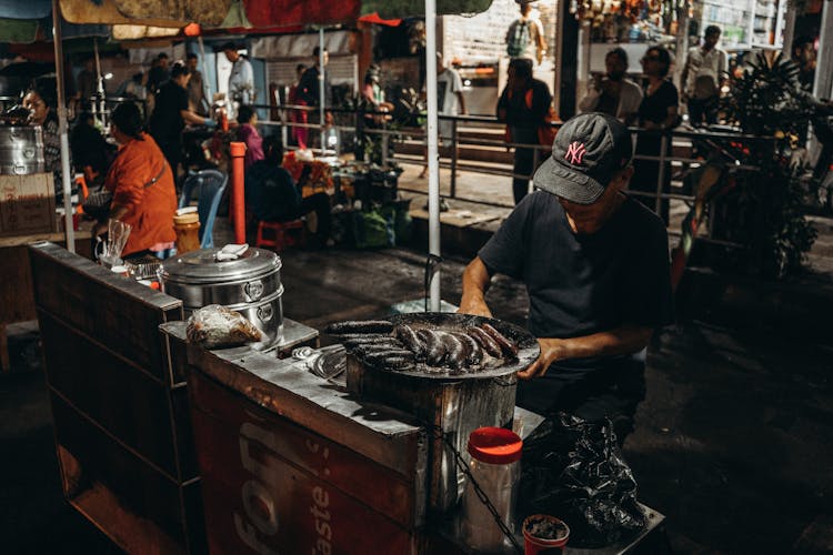 Man Cooking Blood Sausages On Griddle