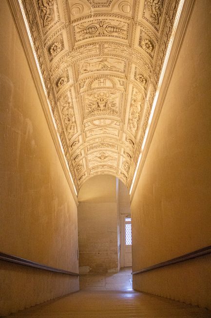 A beautifully detailed ornate ceiling with intricate designs in a historic corridor.