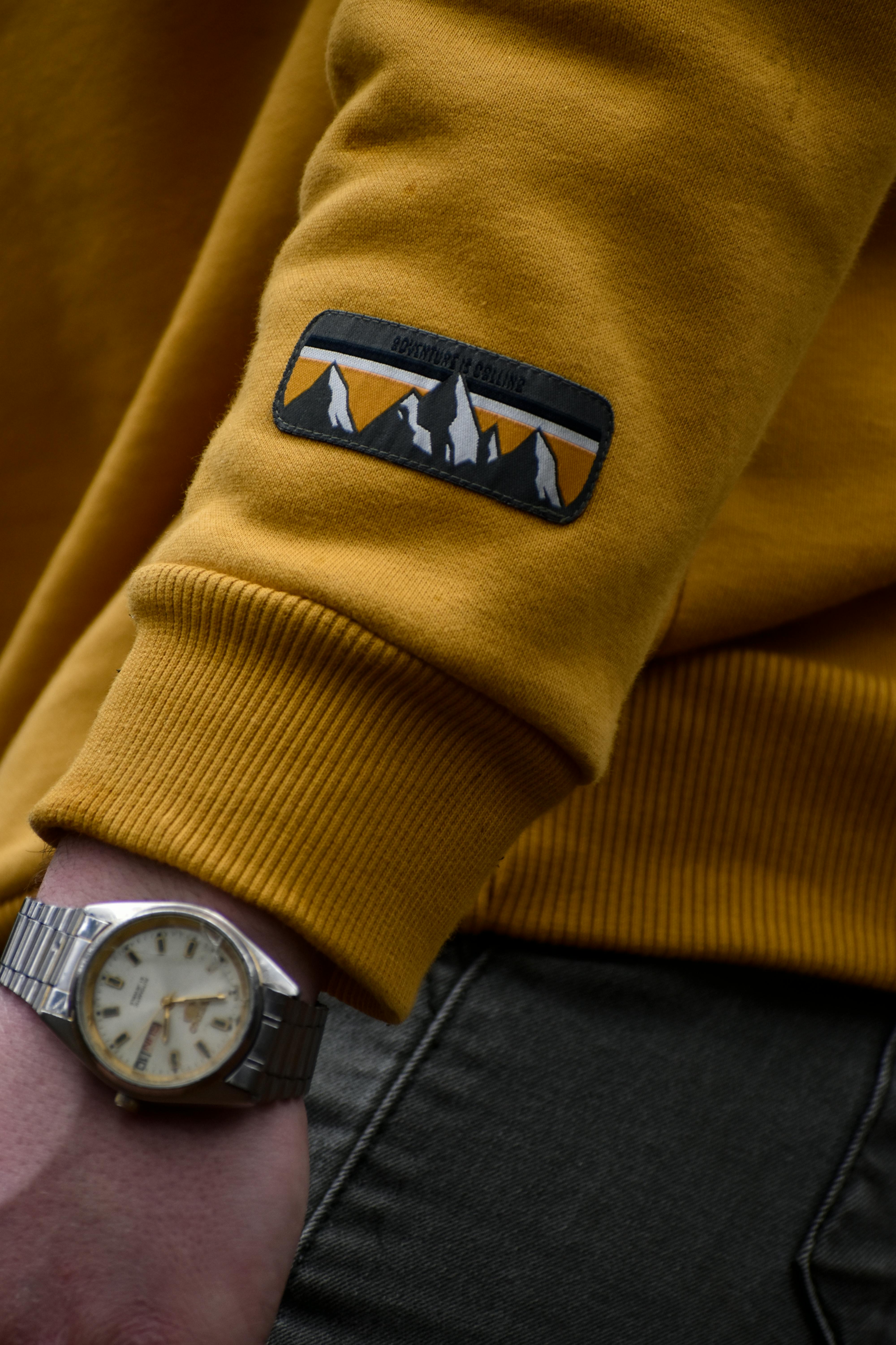 An elegant wristwatch displayed against a vibrant yellow sweater sleeve, showcasing time and fashion.