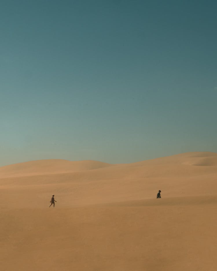 People Walking In The Desert In Distance 