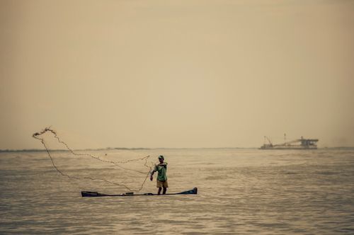 Free A fisherman casting a net in the sea near Rio de Janeiro, capturing the essence of traditional fishing. Stock Photo