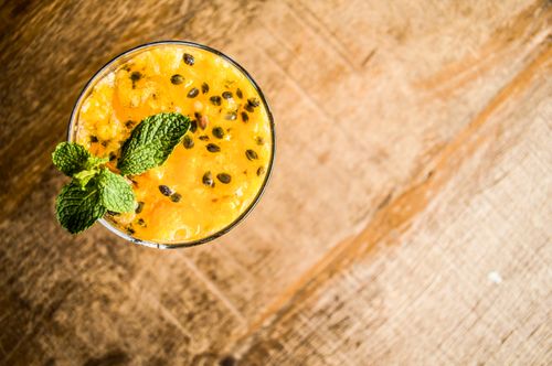Free Top view of a refreshing passion fruit drink garnished with mint leaves on a rustic wooden table. Stock Photo