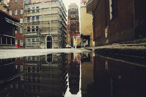 Concrete Building Reflecting On Puddle Of Water 