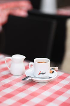 Close-up of espresso in a café setting with a red checkered tablecloth.