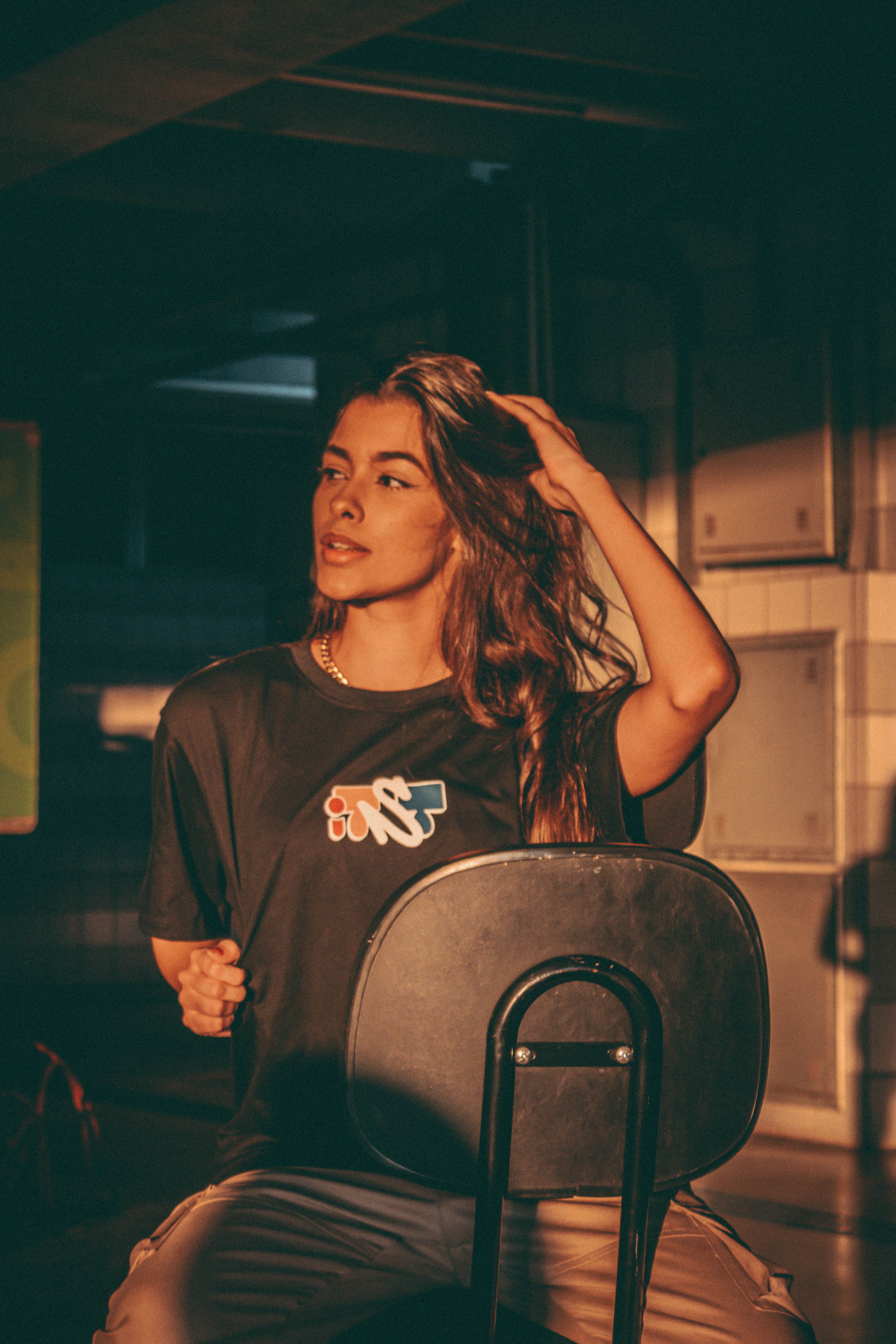 Portrait of a woman sitting indoors with dramatic lighting and posing thoughtfully.