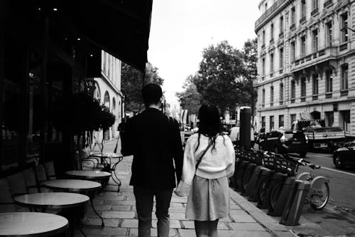 Grayscale Photo of a Couple Walking on the Sidewalk
