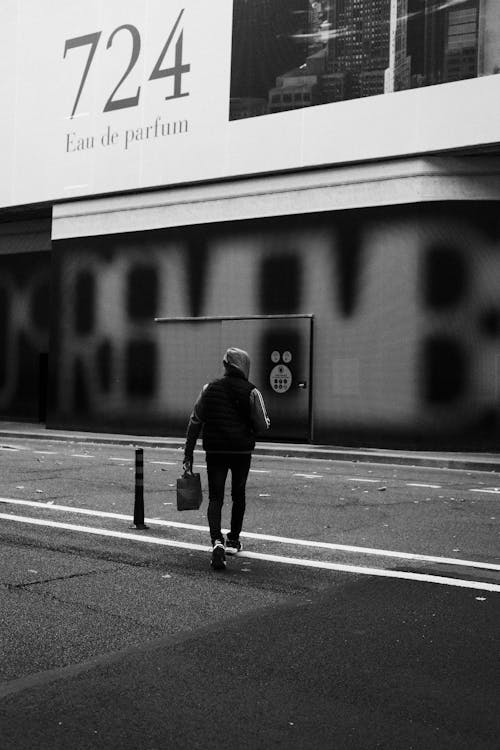 Grayscale Photo of a Man Crossing the Road