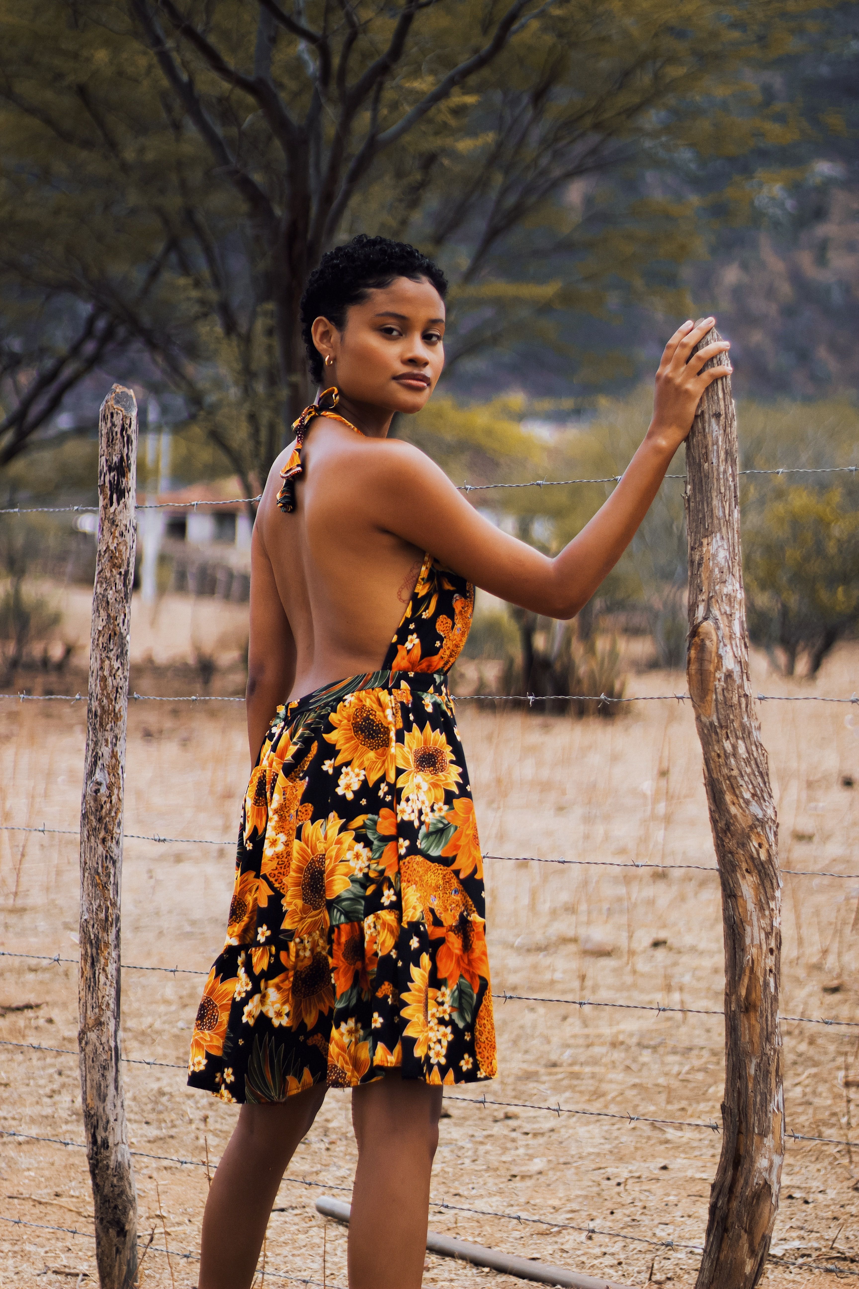 Woman in Floral Dress Standing Beside a Fence · Free Stock Photo