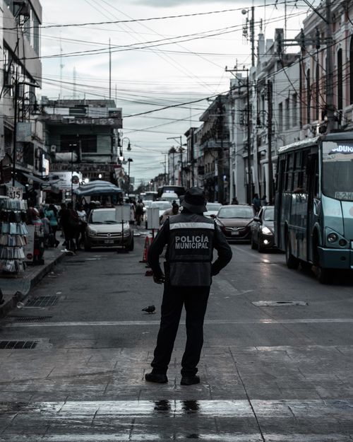 Free Municipal policeman managing city traffic on a bustling street with vehicles and pedestrians. Stock Photo