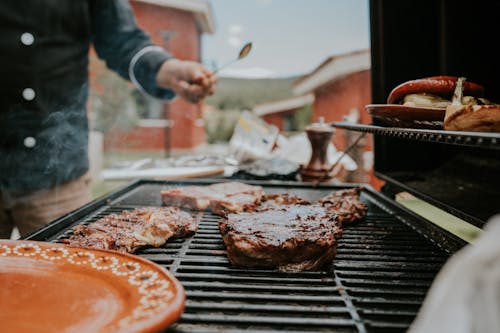 Person Cooking Meat on Charcoal Grill