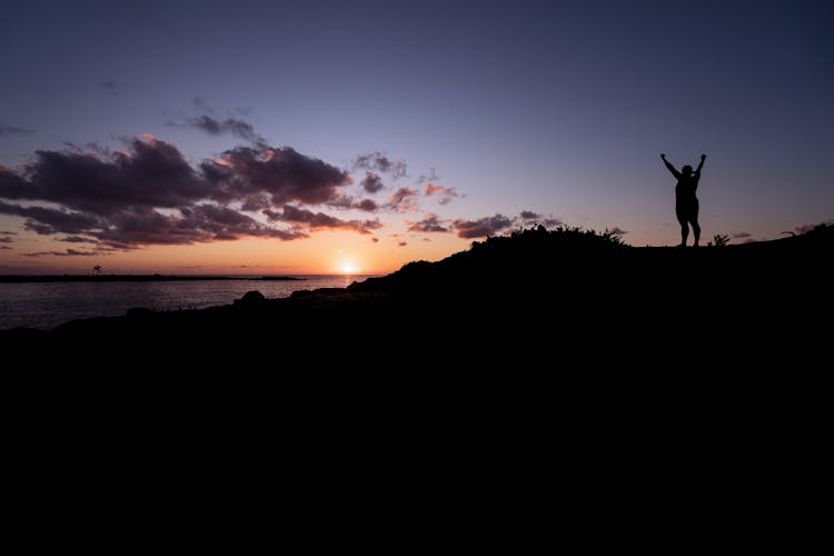 Silhouette Of Person Raising Hands