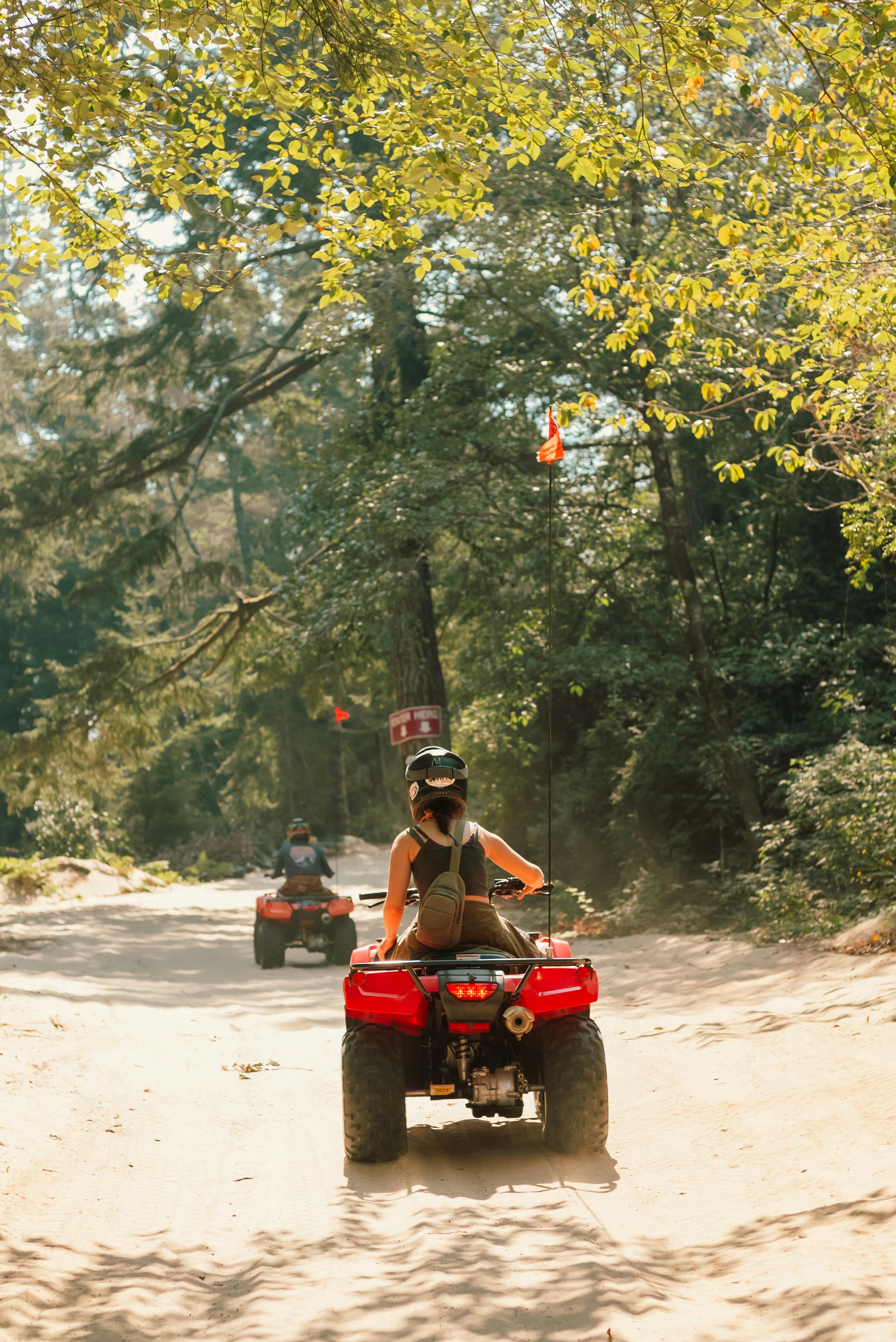 Woman enjoys a thrilling ride on an ATV through a scenic forest trail during a sunny day.