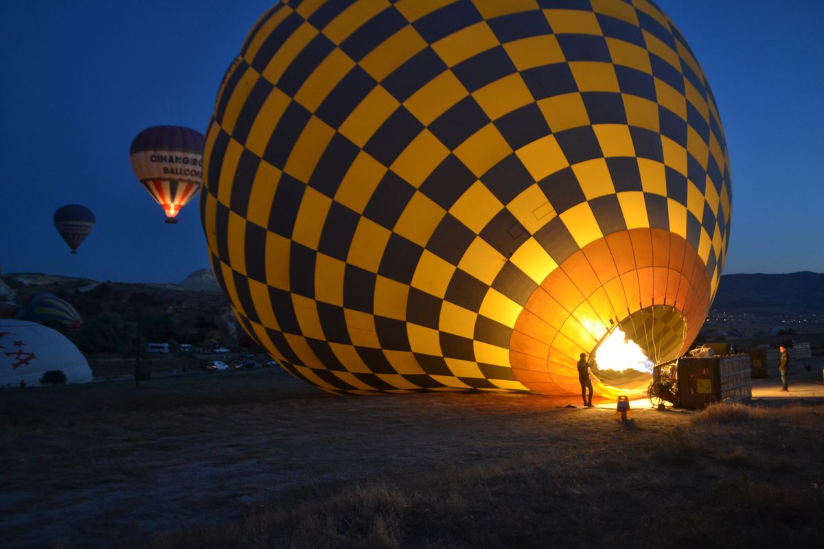A hot air balloon being inflated at dawn in Cappadocia, creating an adventurous scene with vibrant colors.