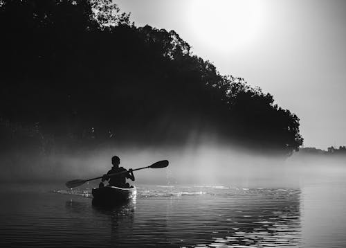 A Silhouette of a Man Paddling a Boat