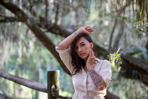 Woman with Arm Tattoo Posing Beside a Tree