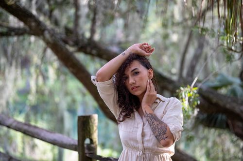 Free A woman with curly hair posing outdoors with an intricate arm tattoo. Stock Photo