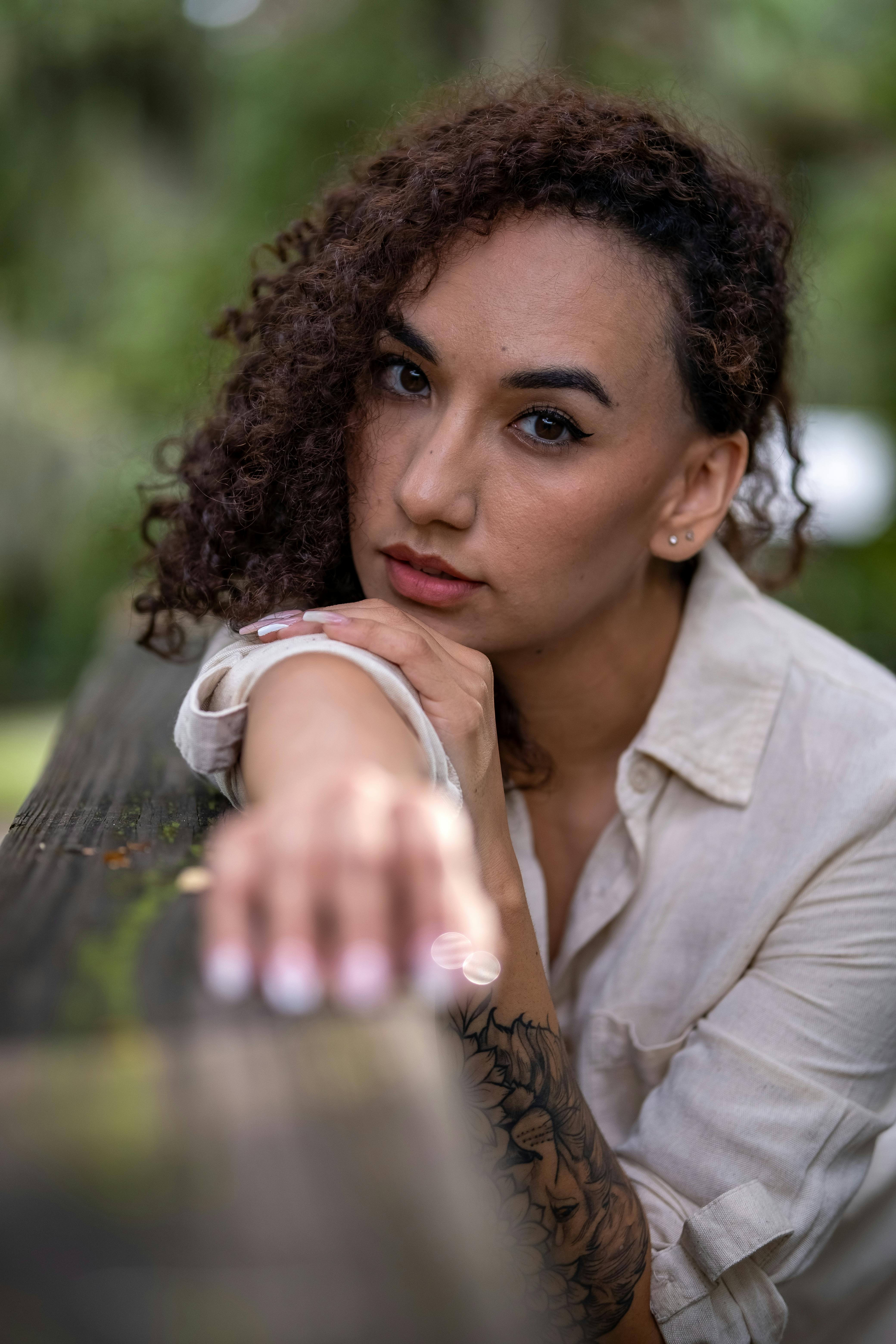 Close-up shot of a woman with curly hair leaning forward outdoors, conveying a calm and natural vibe