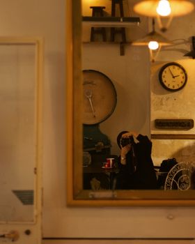 A woman in hijab takes a photograph through a vintage mirror, capturing a cozy indoor scene.