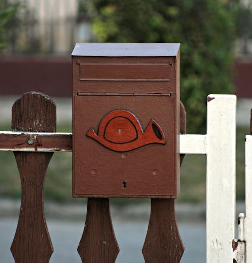 Brown Postbox Hanging on Wooden Fence