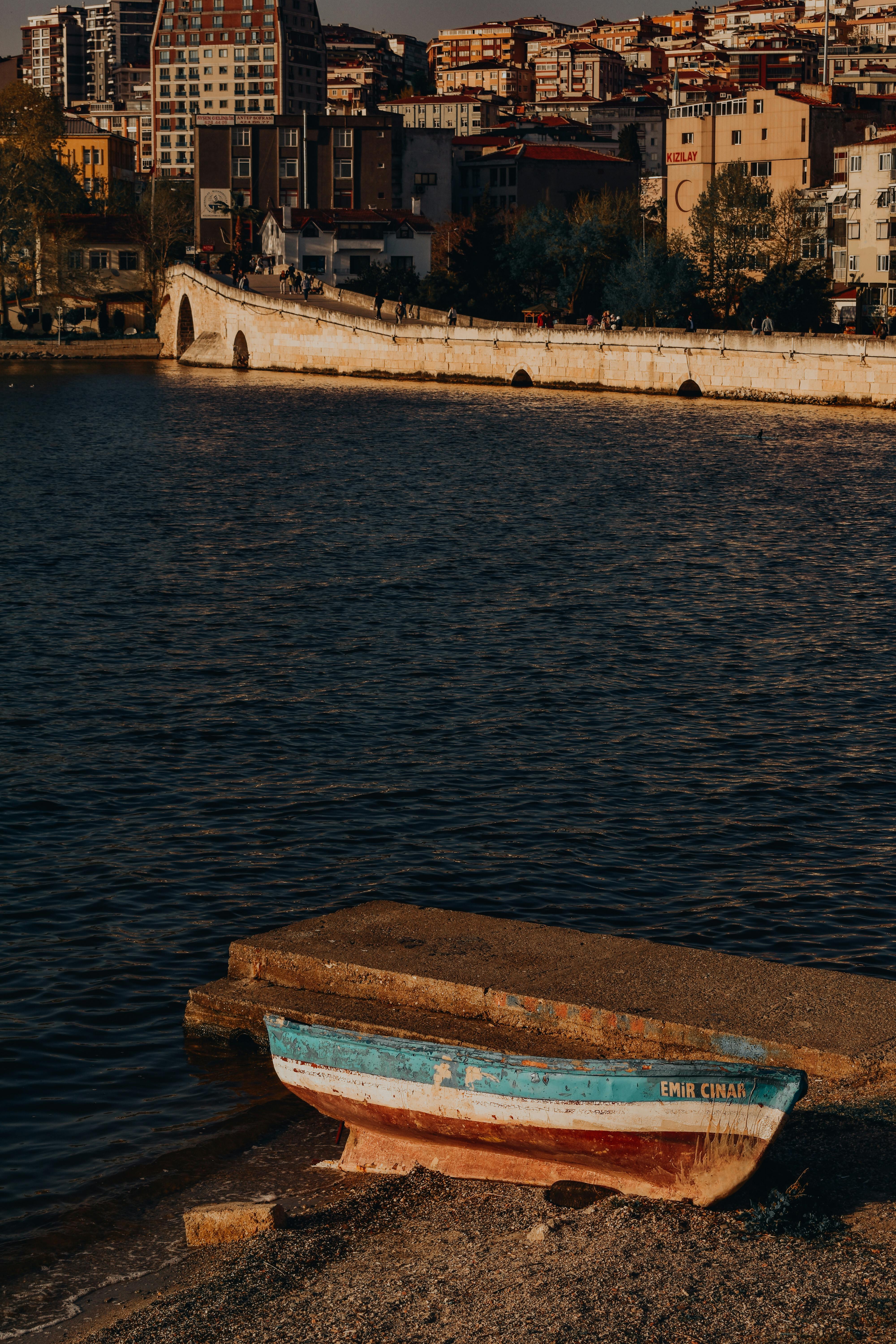 A tranquil scene featuring a colorful boat on the shore with historic architecture in Istanbul.