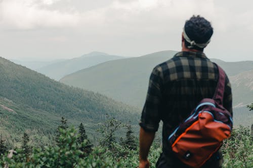 Man in Plaid Shirt Standing Near Mountains