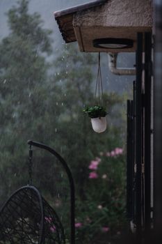 Hanging plant pot outside a house during a rainy evening in Ajaccio, France.