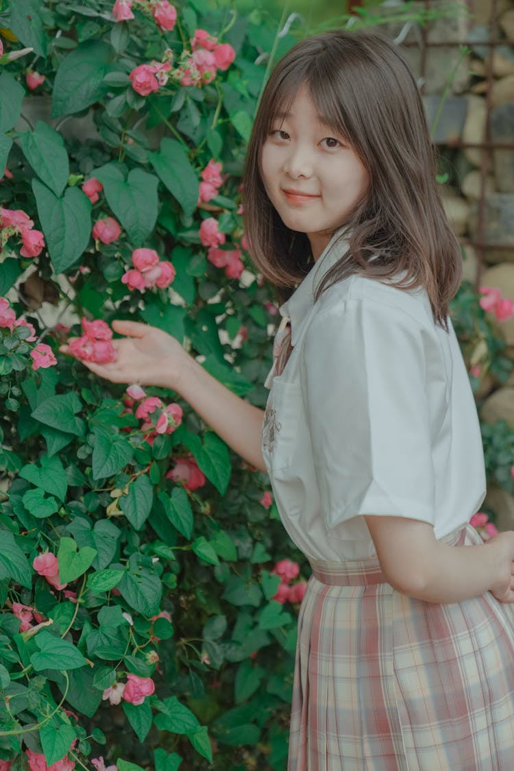 Woman Standing Near Bush With Flowers