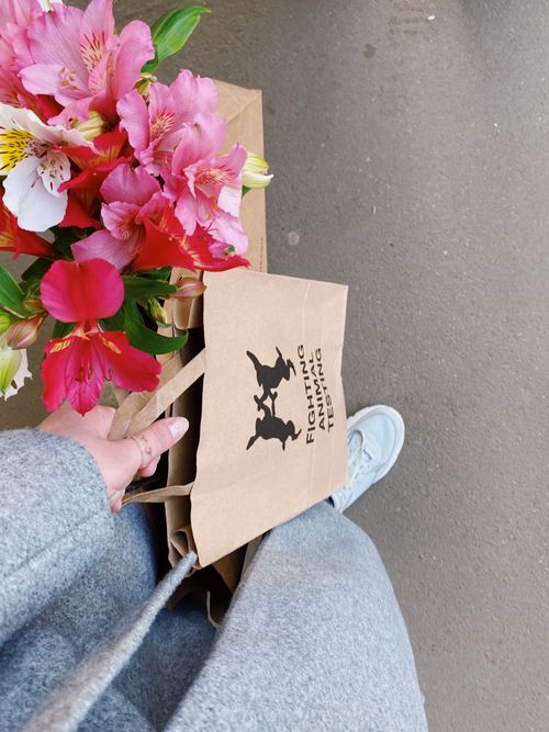 Free A person holds a vibrant floral bouquet and paper bag with anti-animal testing message. Stock Photo