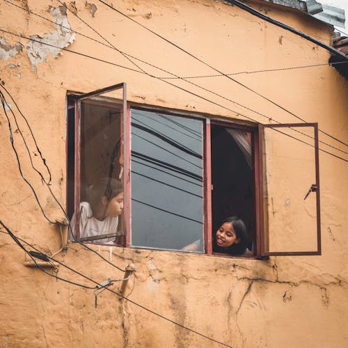 Girls Looking Out the Window of an Old House 