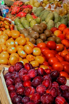 A colorful assortment of fresh fruits including plums, kiwis, and dragon fruits at a Mexican market.