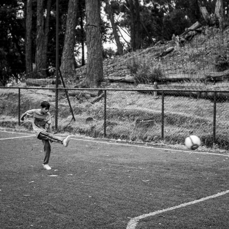 Grayscale Photo Of A Boy Playing Soccer