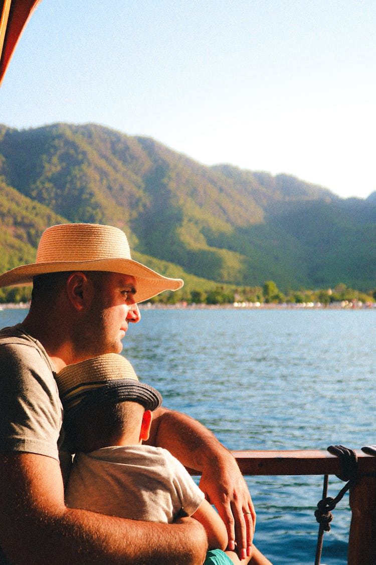 Man With Child In Straw Hats Near Lake