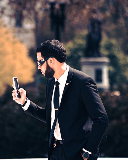 Bearded Man in Black Suit Holding His Cellphone