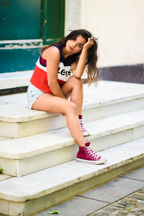 A Woman Wearing Tank Top while Sitting on Stairs Near the Street