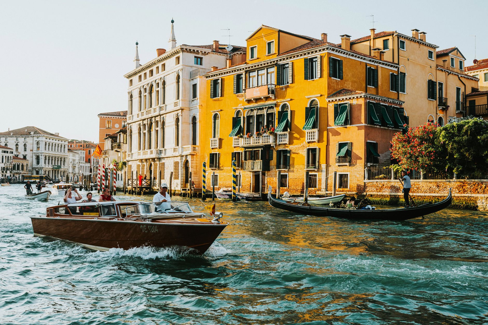 Scenic view of Venice's Grand Canal with gondolas and motorboats passing historic buildings.