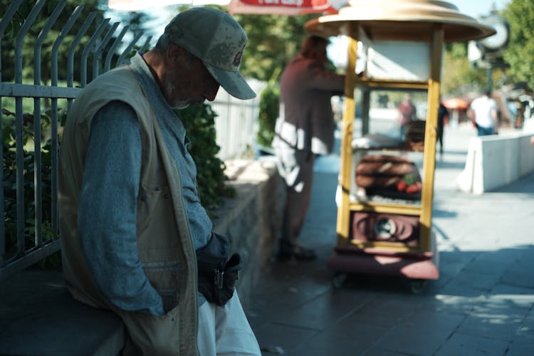 Side View Of Man Wearing Vest And Cap Looking Down 