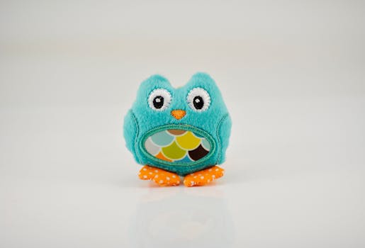 这款可爱的青色猫头鹰毛绒玩具，在白色背景上印有明亮的图案，非常适合孩子们