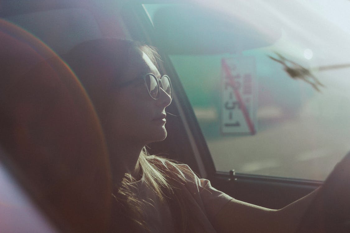 A Woman with Sunglasses Driving a Car