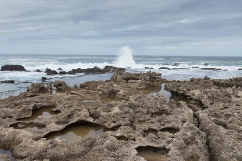 Free Waves crashing on rocky shore under a cloudy sky. Nature's dramatic coastline scene. Stock Photo