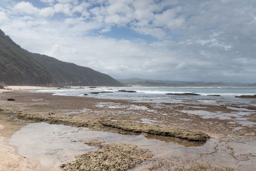 Free Rocky shoreline meets the sea under a cloudy sky, capturing the natural beauty of a serene coastal landscape. Stock Photo