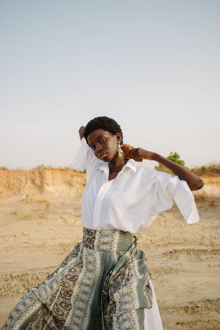 Stylish outdoor portrait of an adult woman in a flowing skirt and white shirt, showcasing elegance and fashion.